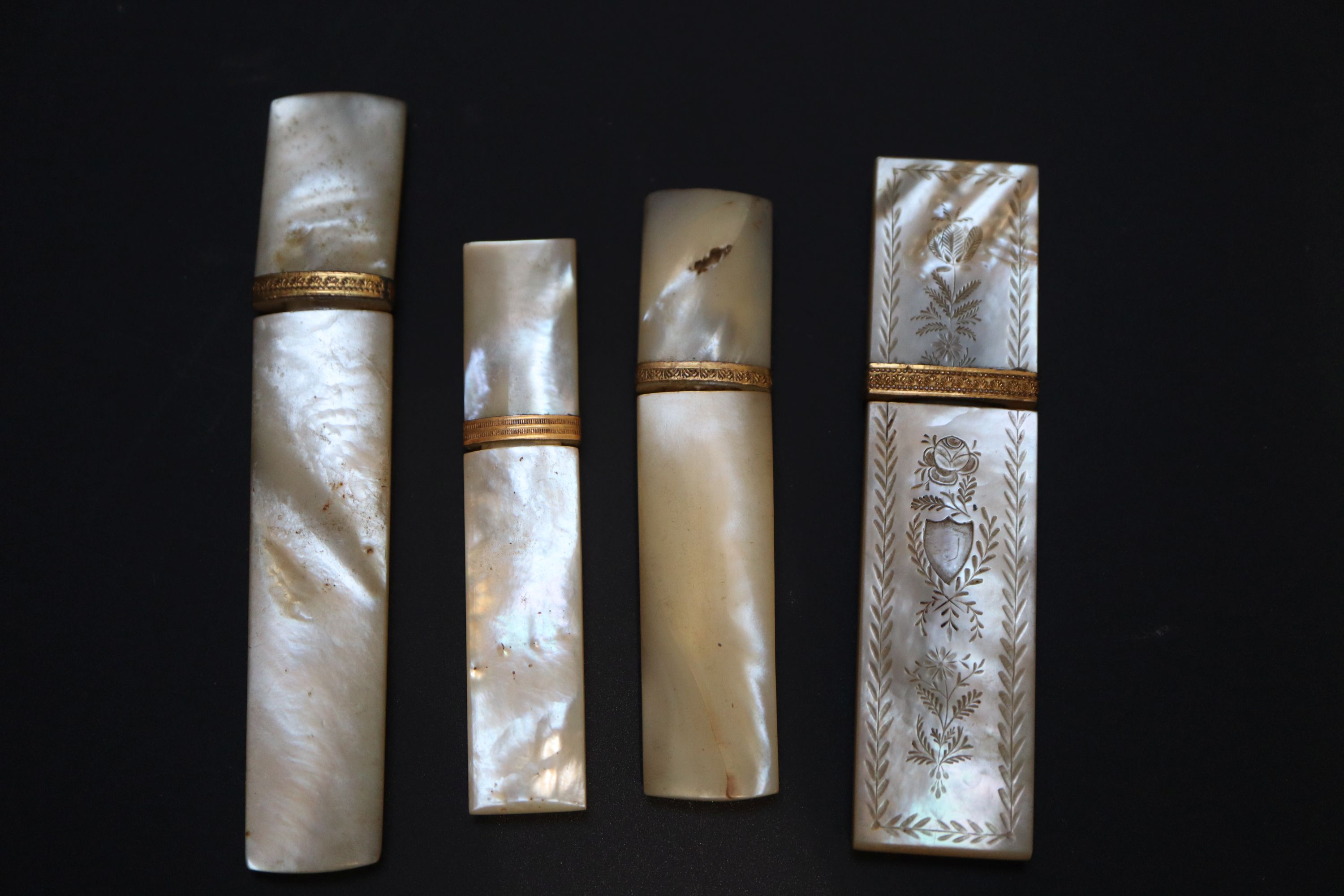 Four 19th century Palais Royale mother of pearl needle cases with gilt mounts, largest 9cm,
